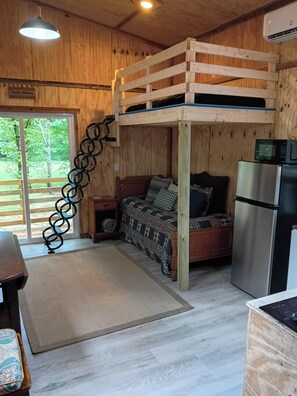 L’intérieur d’une cabine comprenant un lit superposé, un coin cuisine et une vue par la fenêtre.