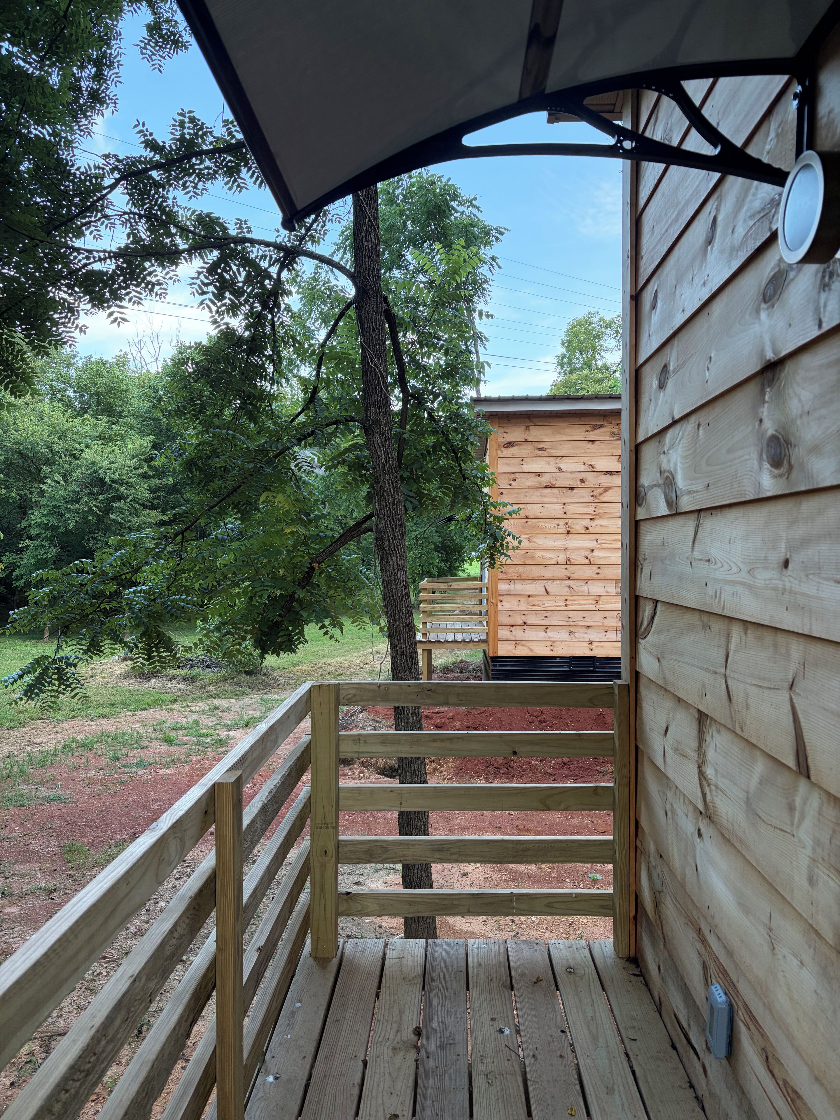 A wooden deck with a railing leading to a building with a sloped roof.