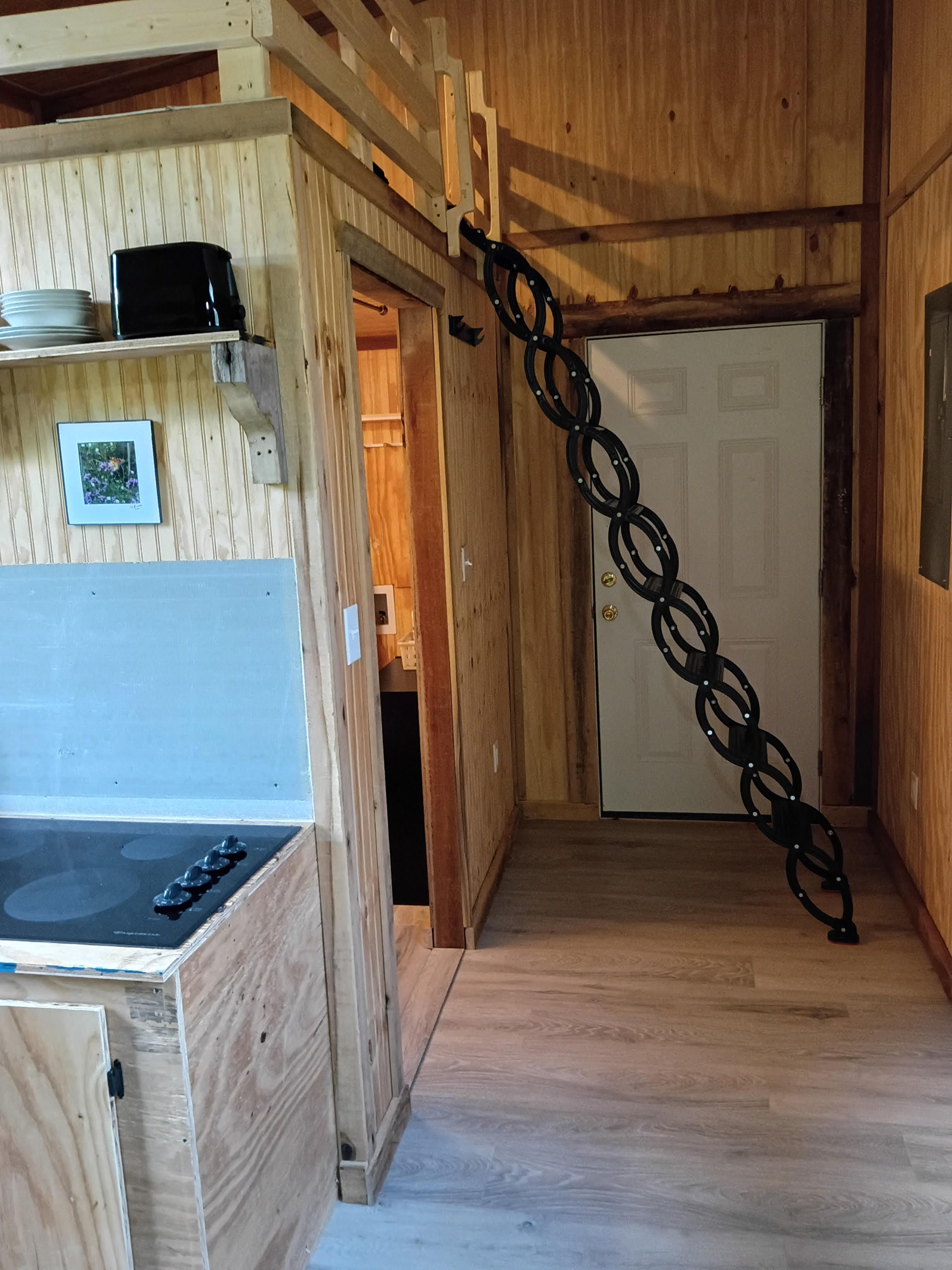 A wooden interior with a kitchen area, a door, and a chain-link decoration.