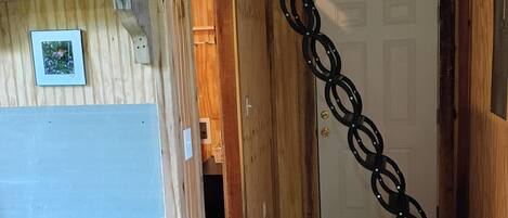 A wooden interior with a kitchen area, a door, and a chain-link decoration.