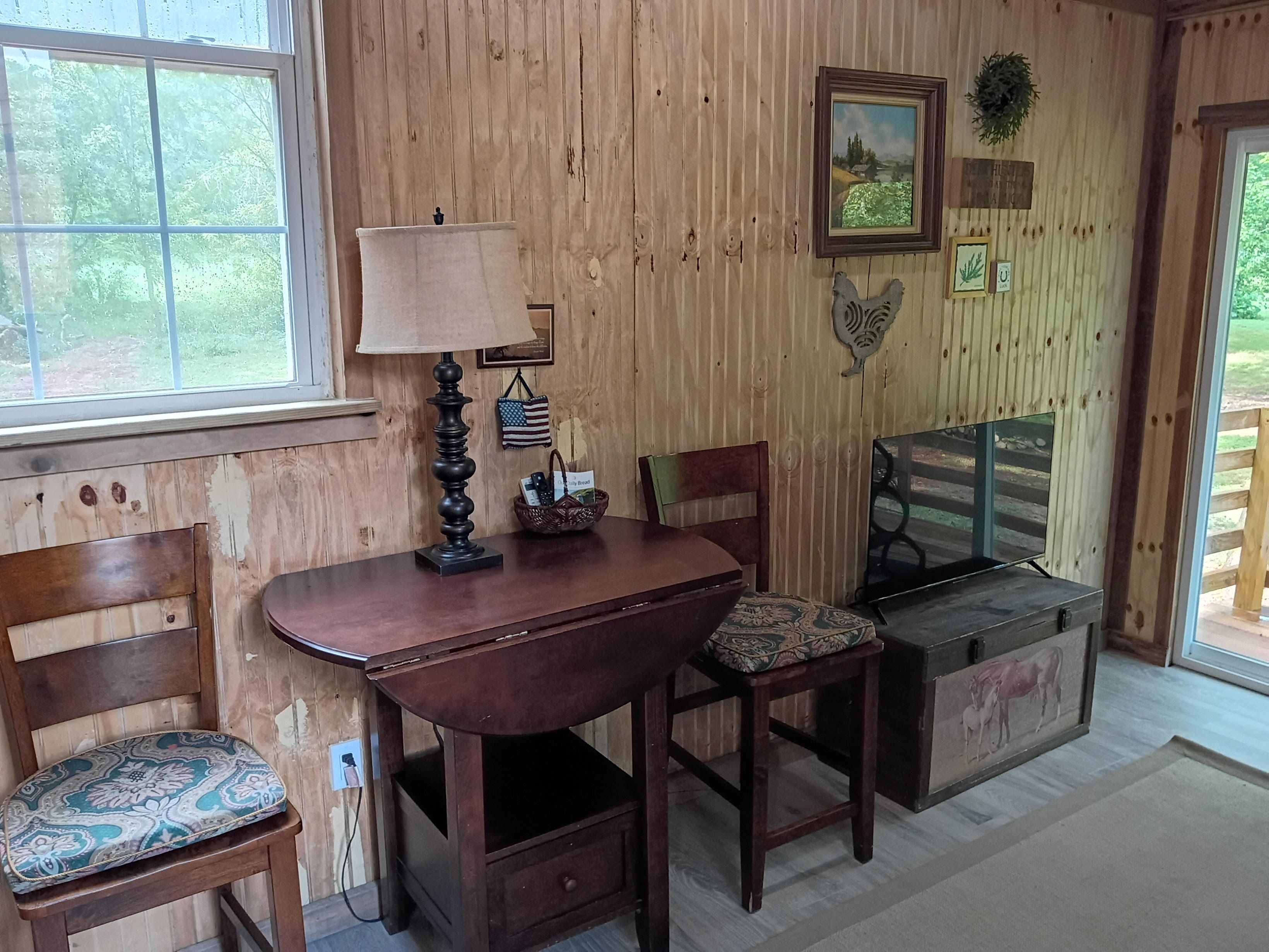 Un interior de madera con una mesa, sillas, una lámpara y un televisor.