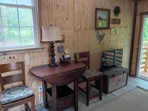 A wooden interior with a table, chairs, a lamp, and a television.