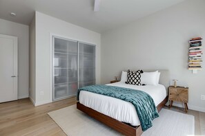 Ein Schlafzimmer mit einem Bett, einem Nachttisch, einem Bücherregal und einem Schiebetürenschrank.