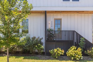 A modern house with a wooden deck, a small garden with hydrangeas, and a clear sky. - The Eastside Darling - Modern 4BR w/ Fenced Yard, East Nashville 30+ Day Stay (Nashville)
