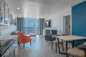 A modern hotel room with a balcony, a dining area, and a TV mounted on the wall. - Coastal Calm Oceanfront Retreat! Yachtsman S700 (Myrtle Beach)