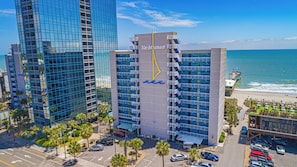 A high-rise building with a prominent 'Yachtsman' sign, surrounded by palm trees and a beach view. - Coastal Calm Oceanfront Retreat! Yachtsman S700 (Myrtle Beach)