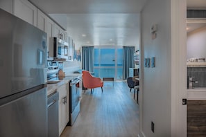 A modern kitchen with stainless steel appliances, a dining area with a view, and a large window. - Coastal Calm Oceanfront Retreat! Yachtsman S700 (Myrtle Beach)