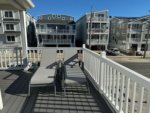 A wooden deck with a white railing, a bench, and a small table. - Cozy Sea Isle City Beach Block Unit - 2nd Floor (Sea Isle City)