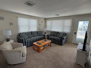 A living room with striped sofas, a coffee table, a lamp, and a television. - Cozy Sea Isle City Beach Block Unit - 2nd Floor (Sea Isle City)