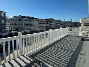 A wooden deck with a white railing, leading to a residential area with multiple houses. - Cozy Sea Isle City Beach Block Unit - 2nd Floor (Sea Isle City)