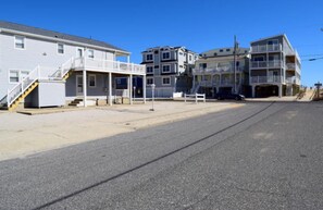 A beachfront residential area with multi-story buildings, including a house with a balcony and a garage. - Cozy Sea Isle City Beach Block Unit - 2nd Floor (Sea Isle City)