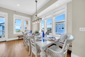 A dining area with a white table, chairs, and a hanging light fixture. - 🌴C'est la Vue | Gulf Views | 3 Pools | Walk to Beach | 3 Levels🌴 (Destin)