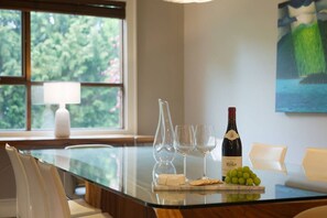 Una mesa de comedor con una botella de vino, copas y uvas.