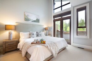 Ein Schlafzimmer mit Bett, Nachttischen, einem Tablett mit Frühstücksgebäck und -zutaten, einem Gemälde und Blick durch ein Fenster.