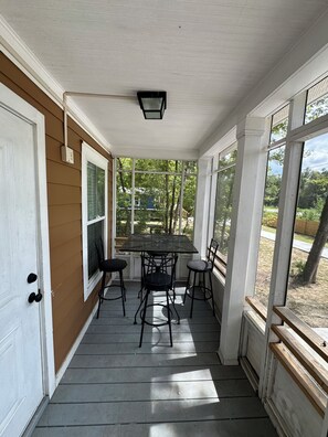 Une véranda avec une table et des chaises, une porte et de grandes fenêtres.