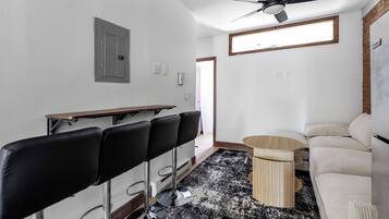 A room with a ceiling fan, a black and white patterned rug, a wooden table, and a beige sofa.