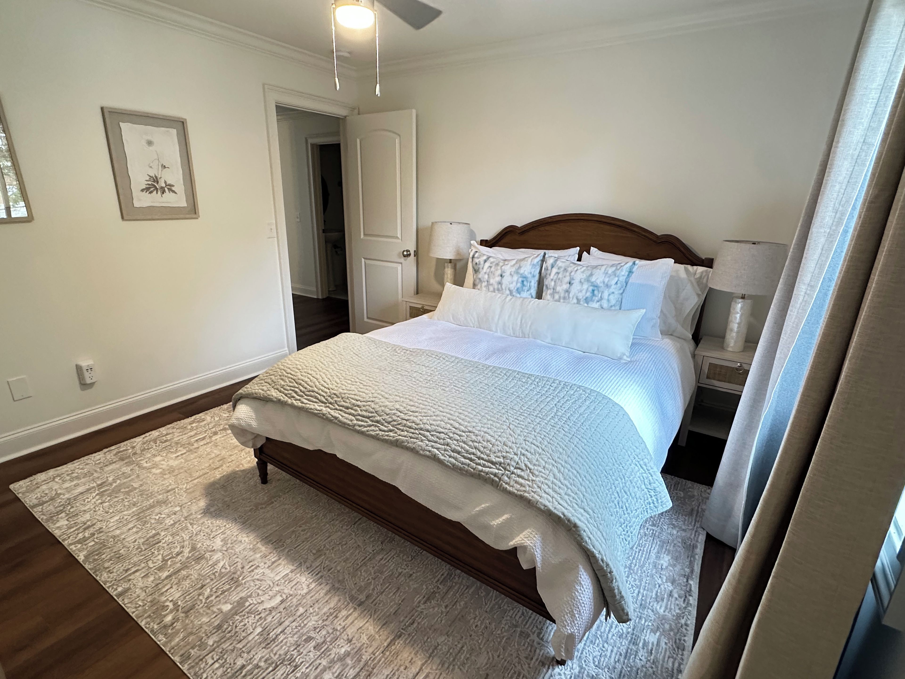Een slaapkamer met een bed, nachtkastjes, een deur en een wandlamp.
