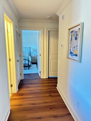 A hallway with wooden flooring leading to a bedroom with a bed and a nightstand. - 2-Bedroom Condo in Auburn-Walk to Stadium and Downtown (Auburn)
