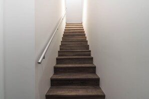 A wooden staircase with a handrail, leading upwards. - The Alpine Den (Revelstoke)