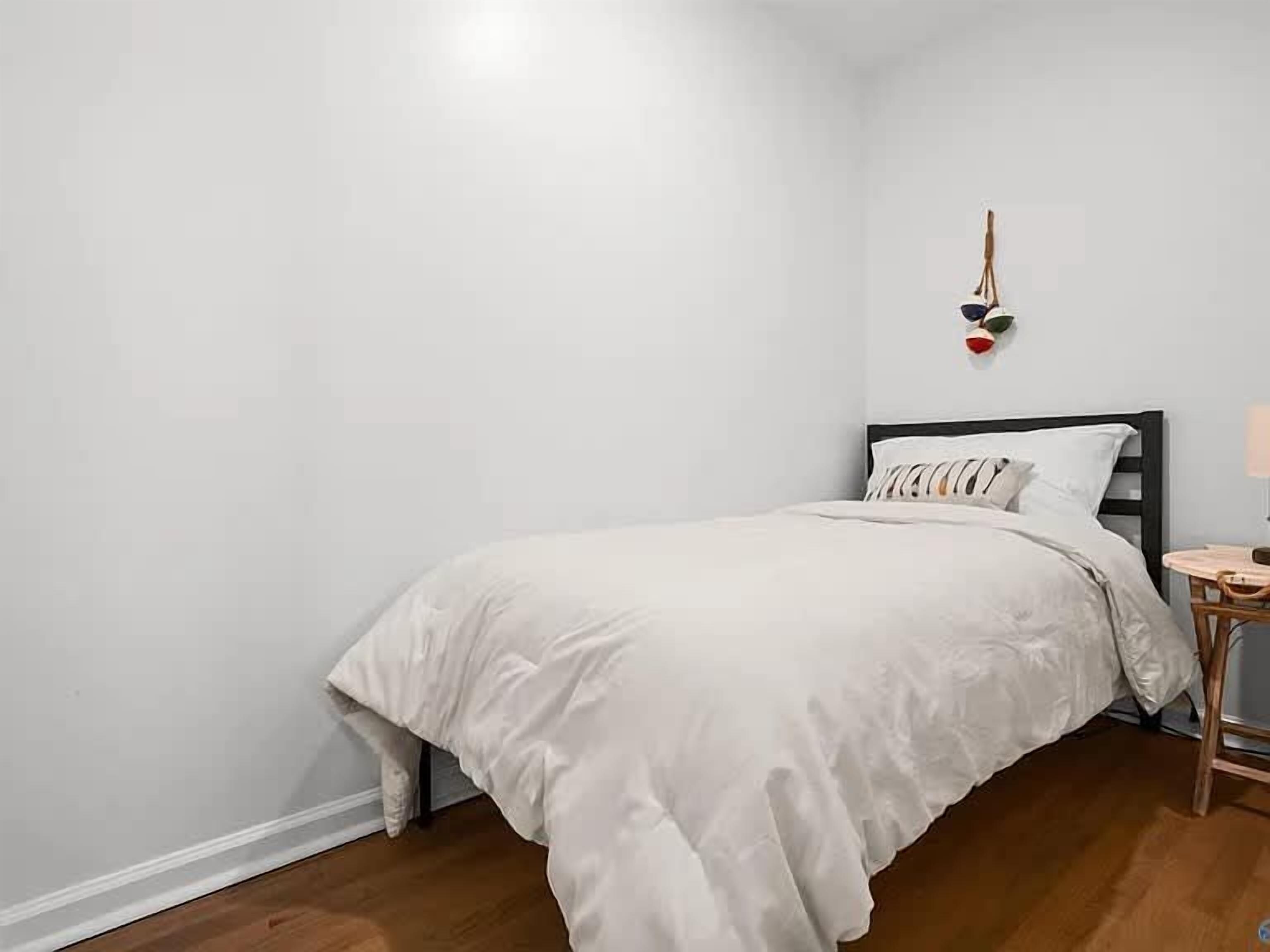 Un dormitorio con cama, mesita de noche y lámpara de pared.
