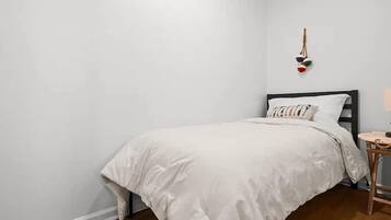 Un dormitorio con cama, mesita de noche y lámpara de pared.