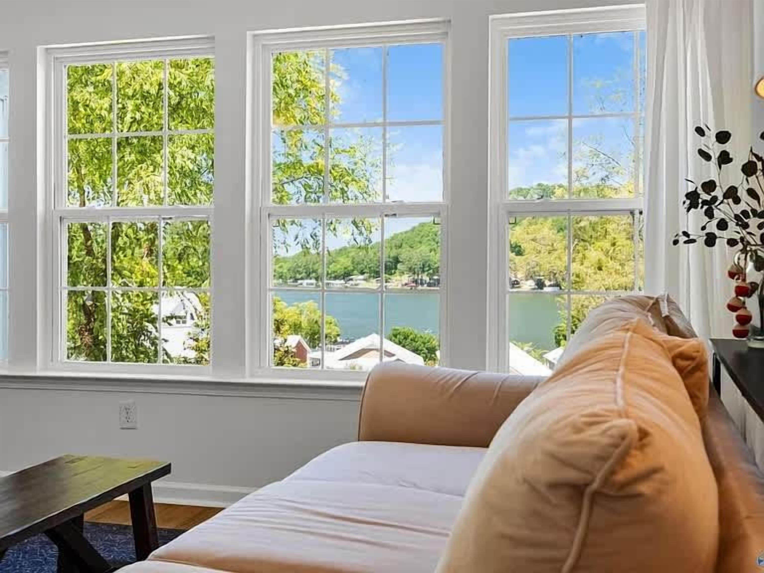 A room with a bed, a window with a view of a lake and trees, and a small table.