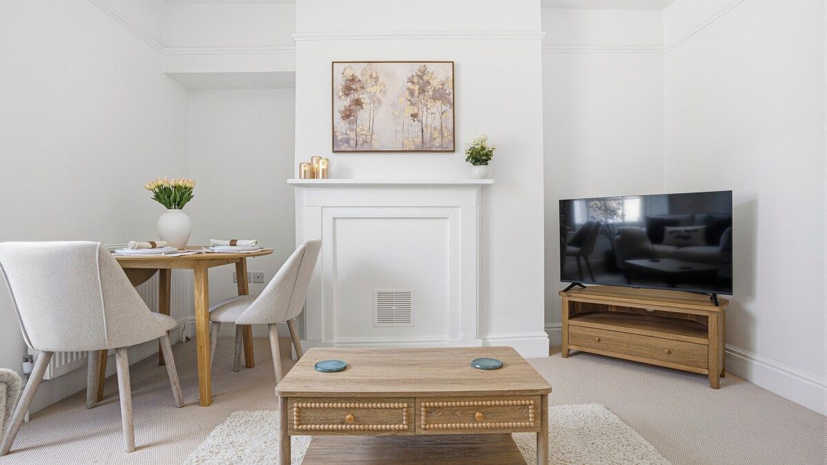 A living room with a fireplace, a television, a dining table with chairs, and a coffee table.