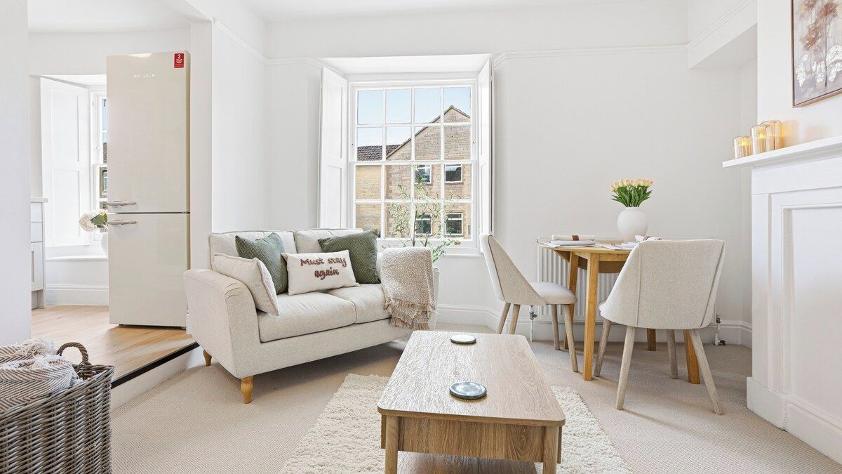 A modern living room with a sofa, a coffee table, and a dining area with chairs.