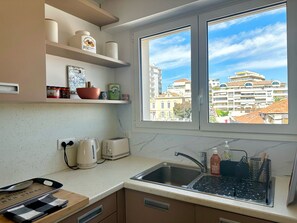 Eine Küche mit Fenster, Spüle und verschiedenen Küchengeräten.