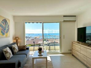 A modern living room with a sofa, a coffee table, and a TV on a wooden cabinet. - Charmant 3P vue mer balcon panoramique, Clim (Cannes)