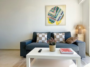 Ein modernes Wohnzimmer mit einer Couch, einem Couchtisch, einer Lampe und einem Bild an der Wand.