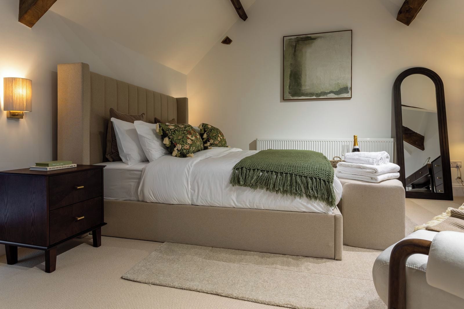 Ein Schlafzimmer mit einem Bett, einem Nachttisch, einer Kommode und einem Spiegel.