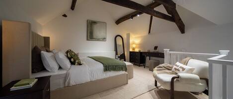 Quarto com cama, cadeira, escrivaninha e espelho.