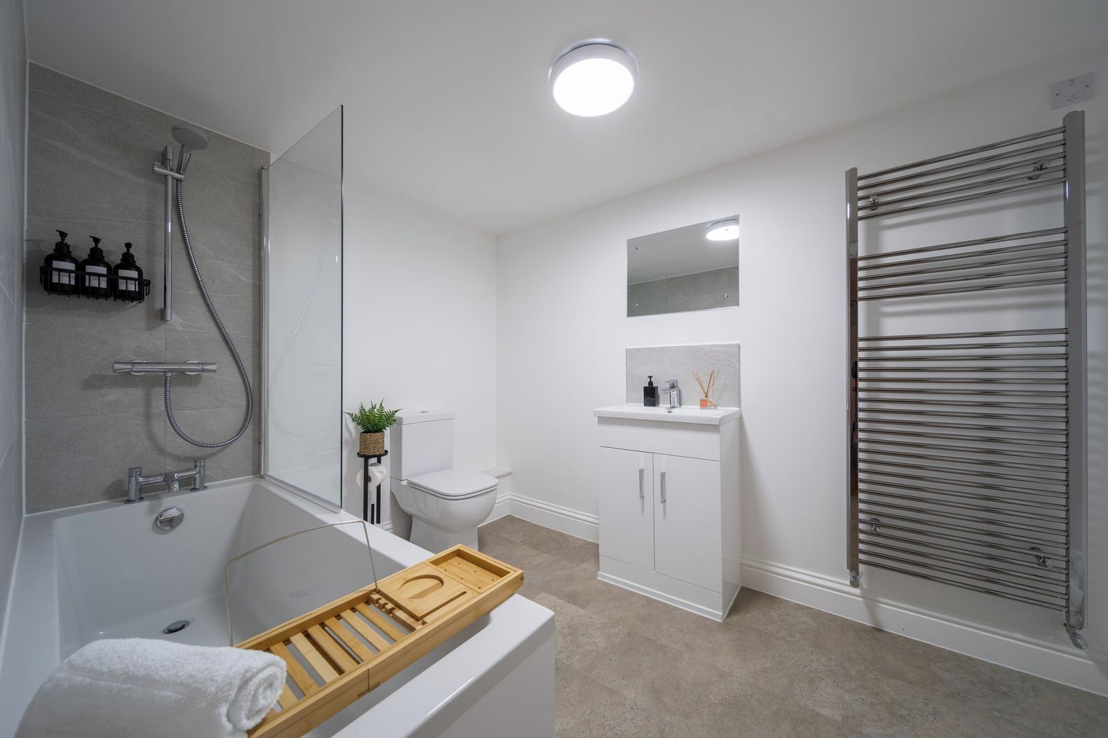 A modern bathroom with a bathtub, toilet, and shower.