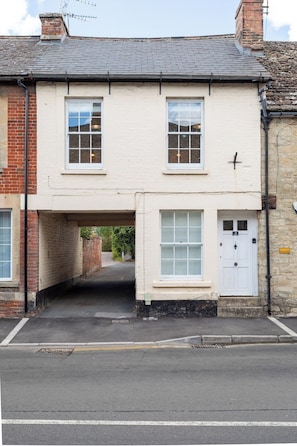 A two-story building with a white facade, a single entrance with a door marked '2', and a small porch area. - New! Stylish King Bed Apartment | Central Lechlade (Lechlade)