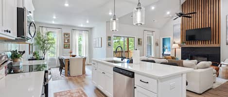 Una cocina moderna con una isla central, armarios blancos e iluminación colgante.