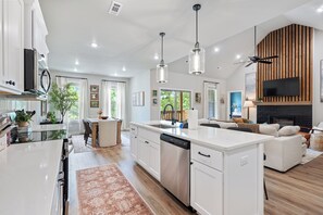 A modern kitchen with a central island, white cabinetry, and pendant lighting. - Trailfront Ride & Reel - Upscale Retreat 4bd/2.5ba Sleeps 10 - HOT TUB! (Bella Vista)