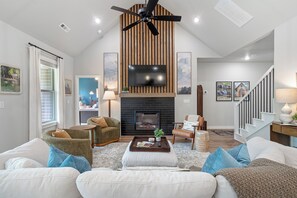 A spacious living room with a fireplace, comfortable seating, and a television mounted on the wall. - Trailfront Ride & Reel - Upscale Retreat 4bd/2.5ba Sleeps 10 - HOT TUB! (Bella Vista)