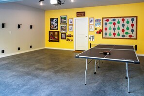 A room with a ping pong table, a door, and various framed pictures on the walls. - Trailfront Ride & Reel - Upscale Retreat 4bd/2.5ba Sleeps 10 - HOT TUB! (Bella Vista)