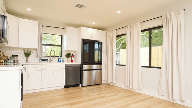 A modern kitchen with white cabinets, stainless steel appliances, and large windows with curtains. - Luxury 3BR Retreat - Modern Comfort in Fort Lauderdale (Fort Lauderdale)