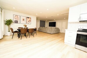 A modern kitchen with a built-in oven and a dining area with a table and chairs.