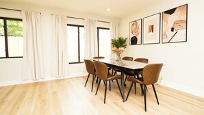 A dining area with a table and chairs, large windows with curtains, and framed artwork on the wall. - Luxury 3BR Retreat - Modern Comfort in Fort Lauderdale (Fort Lauderdale)