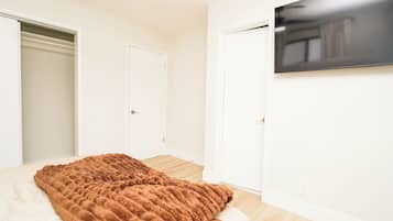 A bedroom with a bed, a TV mounted on the wall, and two doors.
