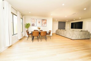 A spacious living area with a dining table, chairs, a sofa, a TV, and artwork on the walls. - Luxury 3BR Retreat - Modern Comfort in Fort Lauderdale (Fort Lauderdale)