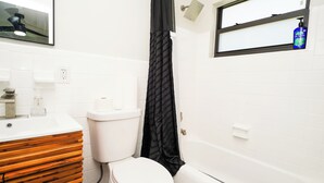 A bathroom with a toilet, a sink, a shower, and a window. - Luxury 3BR Retreat - Modern Comfort in Fort Lauderdale (Fort Lauderdale)