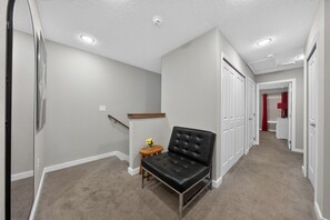 A hallway with a staircase, a bench, and a small table with flowers. - Disney Getaway 4BD Home wITH Private Pool and BBQ (Kissimmee)
