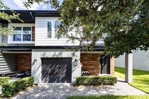 Ein modernes, zweistöckiges Haus mit Garage, überdachter Terrasse und gepflegtem Rasen.