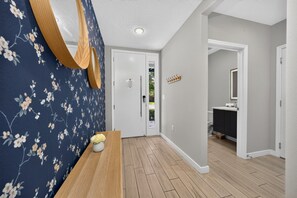 A hallway with a wooden bench, a mirror, and a door leading to a bathroom. - Disney Getaway 4BD Home wITH Private Pool and BBQ (Kissimmee)