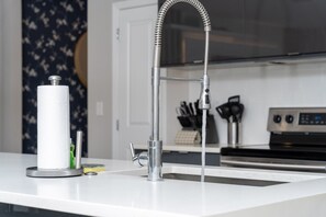 A kitchen with a modern faucet, a paper towel holder, and a knife block. - Disney Getaway 4BD Home wITH Private Pool and BBQ (Kissimmee)