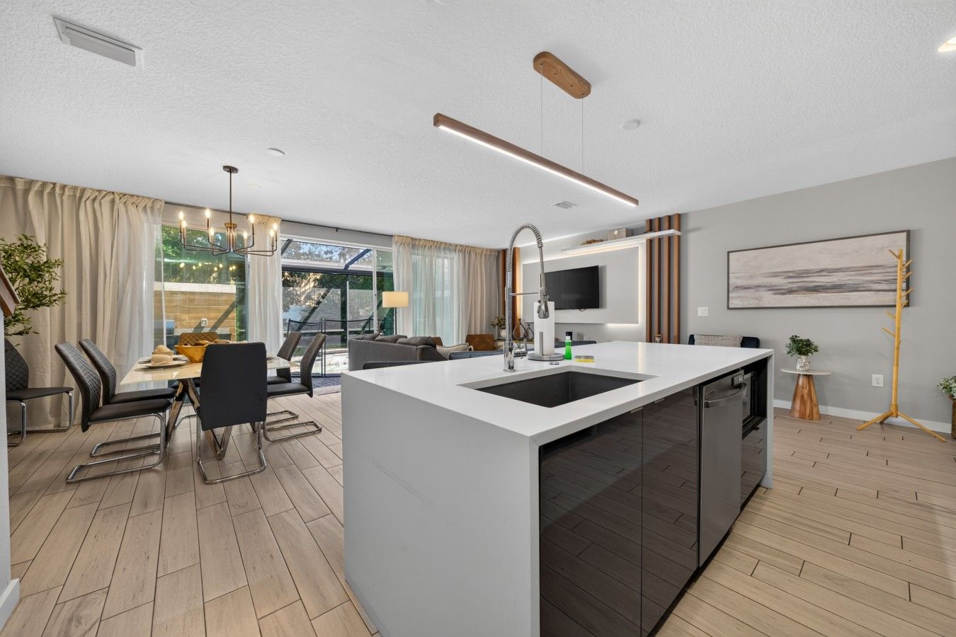 A modern kitchen with a central island, a dining area with chairs and a table, and a large window with curtains.